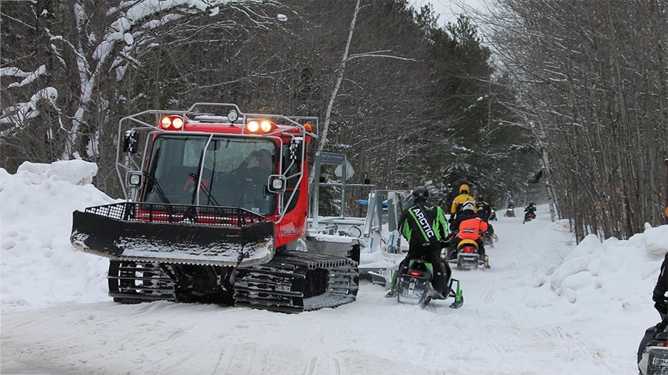 Pisten Bully groomer and passing snowmobiles